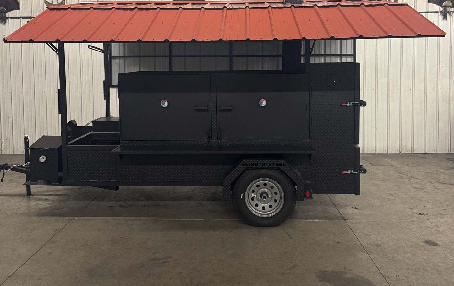 Large black custom BBQ pit smoker on trailer with collapsible red roof and sink package