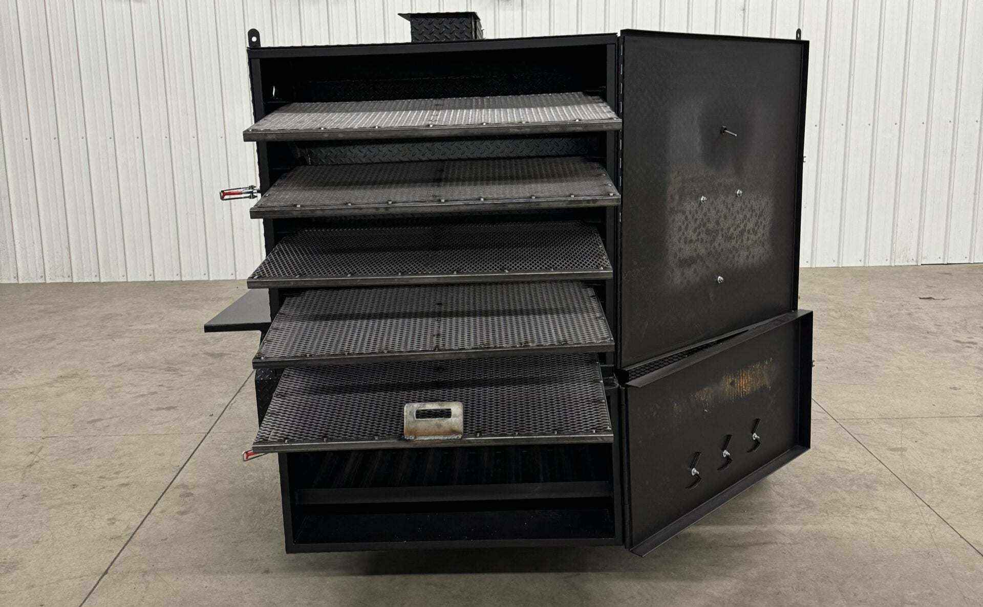 Custom charcoal grill and SNS 4060 smoker with multiple racks and open doors on concrete floor