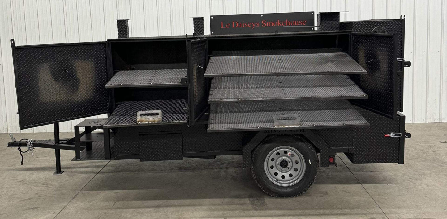 Custom charcoal grills and smoker trailer with multiple cooking racks and open doors showing cooking chambers designed for versatile catering and barbecue smoking.