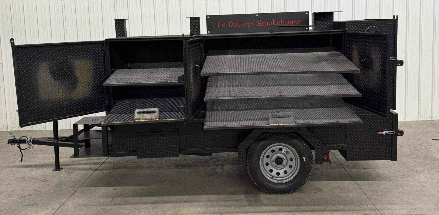 Custom charcoal grill trailer with multiple smoking racks and side compartments for catering use