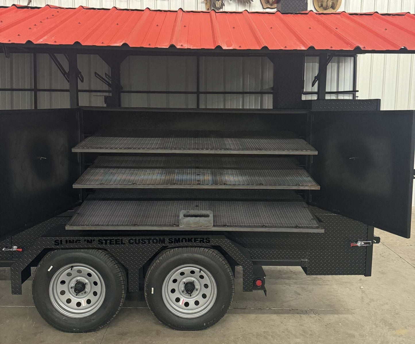 Open 72-inch ultimate smokehouse smoker on black trailer with three pull-out cooking racks and red roof