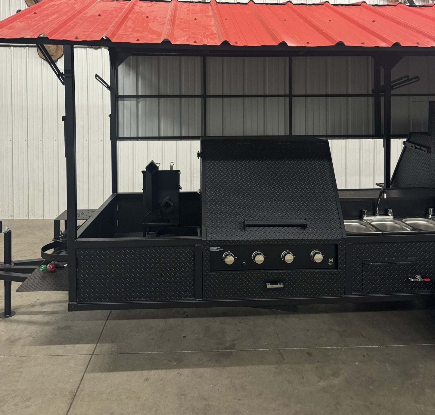 Ultimate Smokehouse 72-inch smoker on trailer with red roof, charcoal grill, propane griddle, sink, and multiple cooking racks