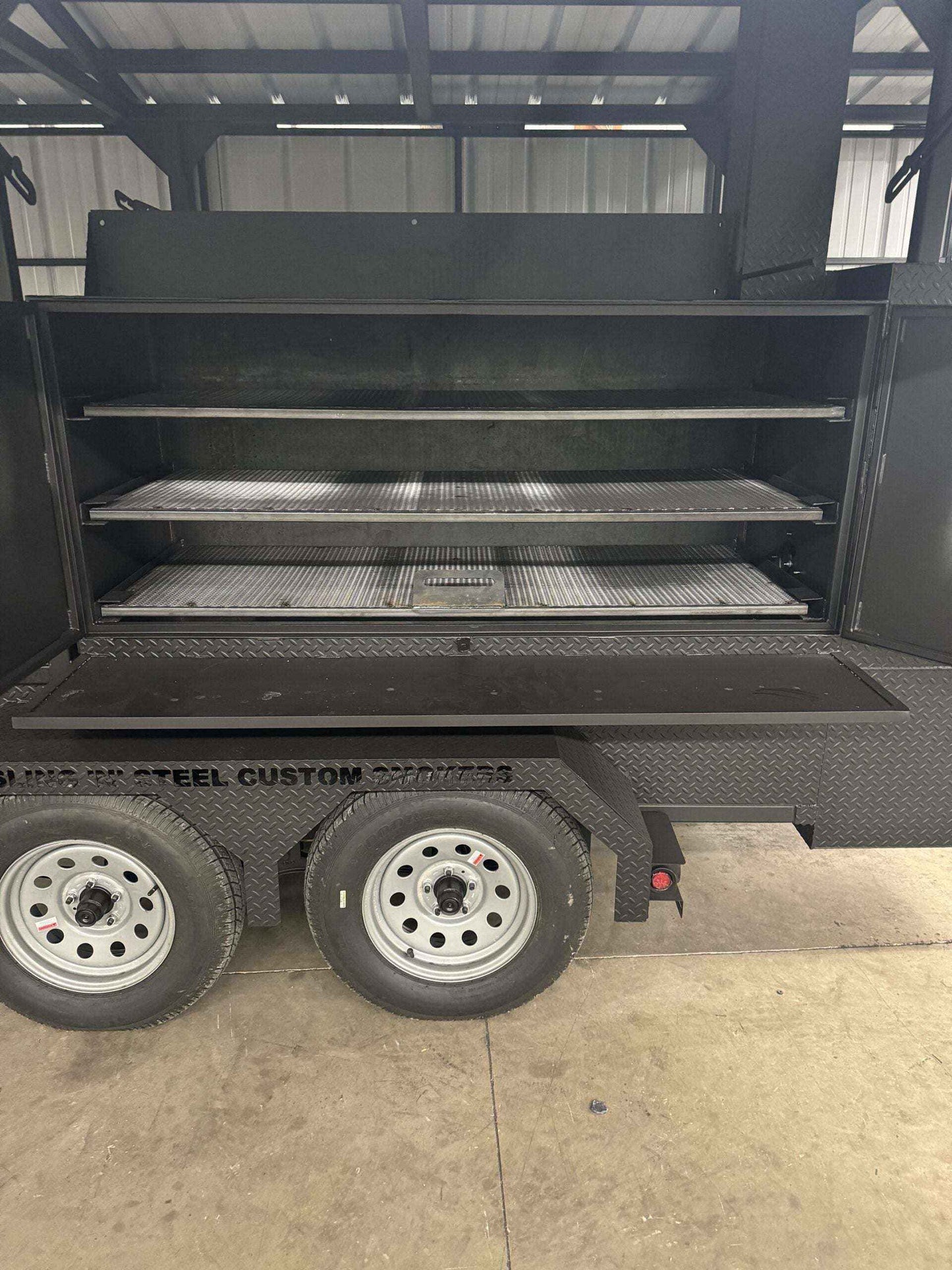 Custom Ultimate Smokehouse 72-inch commercial smoker with multiple pull-out cooking racks and charcoal grill on trailer wheels