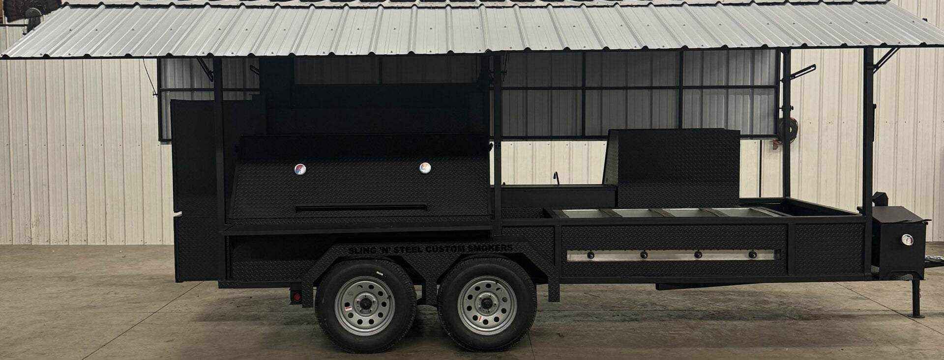 Custom Ultimate Smokehouse 72-inch commercial smoker with griddle, sink package, and charcoal grill on trailer under metal roof