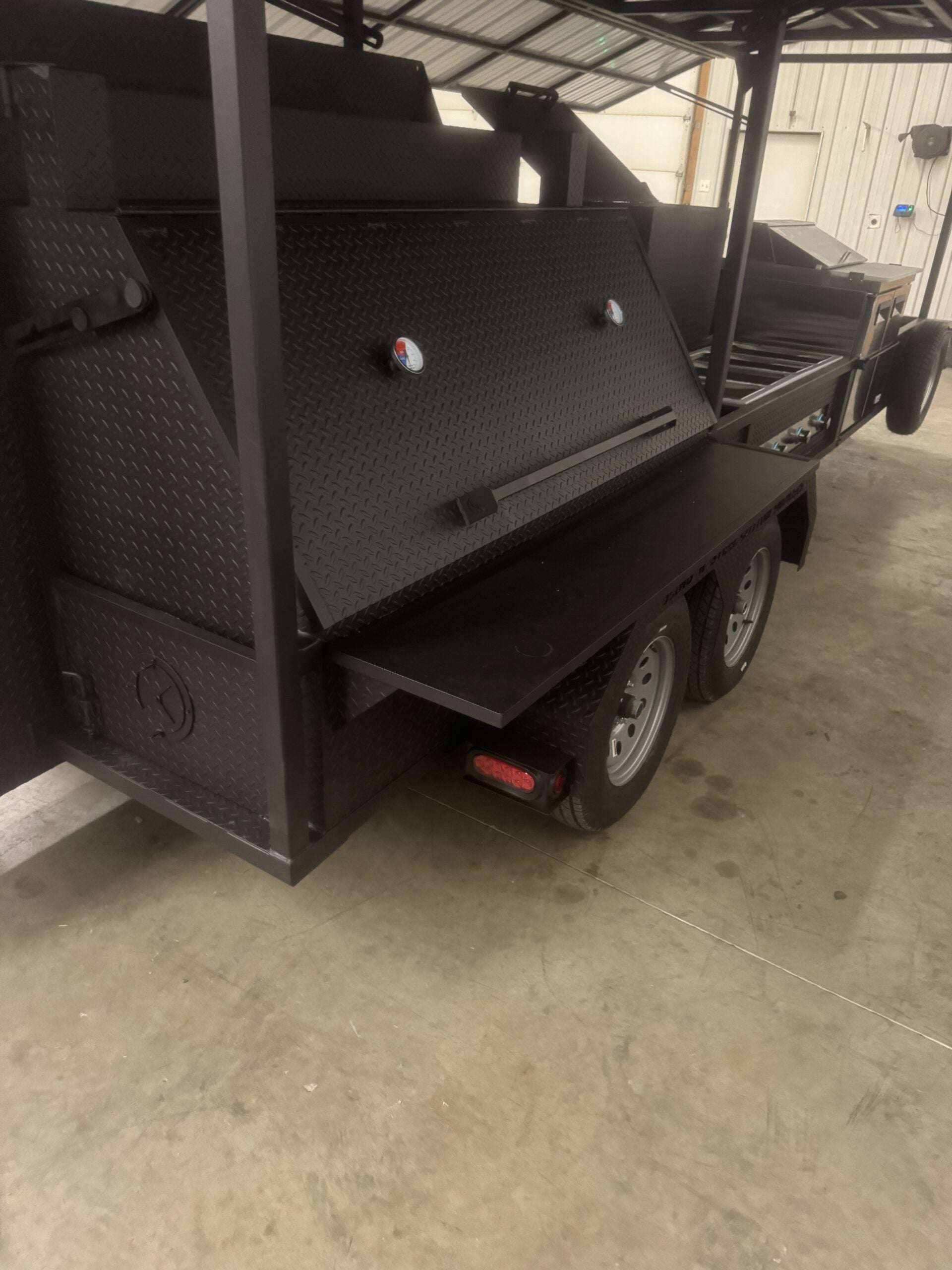 Custom Ultimate Smokehouse 72-inch smoker trailer with roof, sink, charcoal grill, sandwich prep refrigeration, and multiple cooking racks