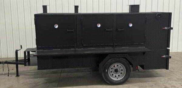 SNS 4060 Cabinet Smoker with charcoal grill on trailer, black steel construction, multiple cooking racks, and insulated firebox for versatile catering use