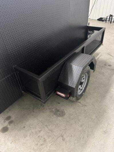 SNS 4060 Cabinet Smoker with diamond tread steel exterior, charcoal grill, insulated firebox, slide-out cooking racks, and storage basket on a trailer frame