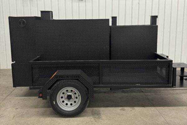 Black smoker grill trailer with cabinet main chamber and full storage basket on a single axle trailer