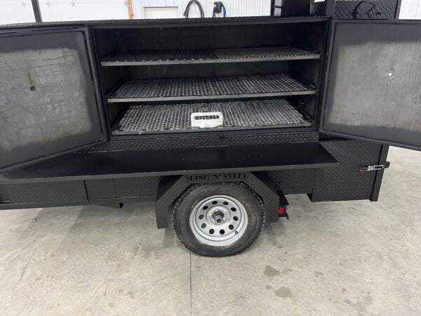 SNS 60 Cabinet Smoker showing open doors with three slide out cooking racks inside on trailer wheelbase