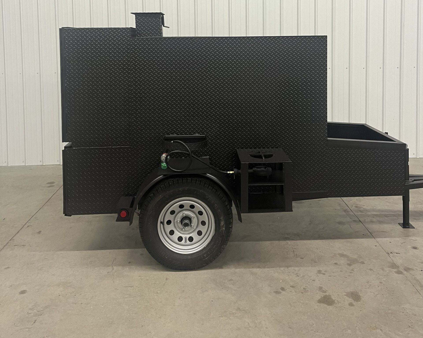 SNS 60 Cabinet Trailer Smoker made of black diamond tread steel with large cooking chamber and insulated firebox on a single-axle trailer.