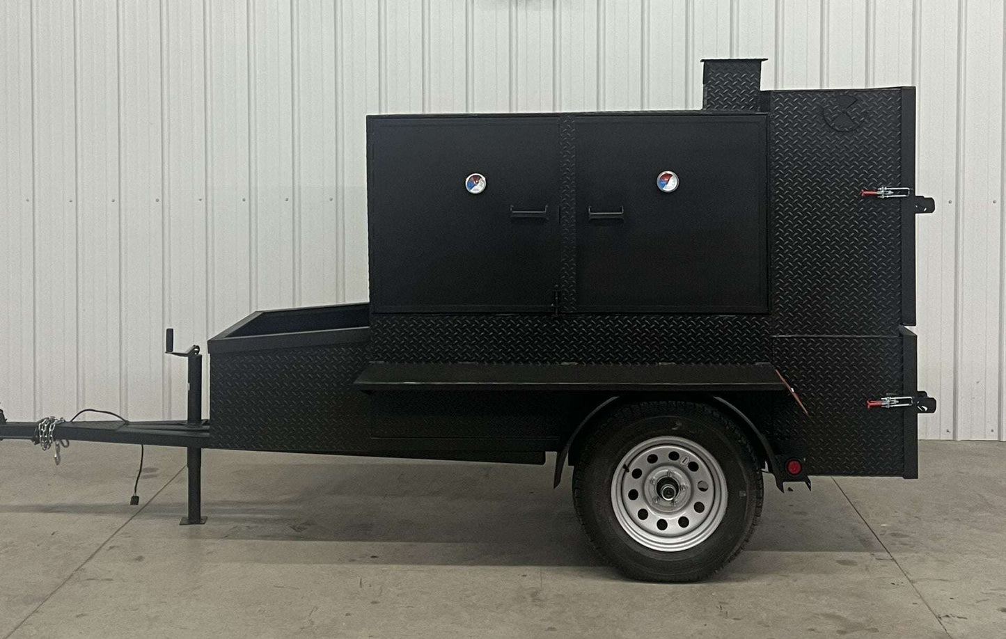 SNS 60 Cabinet trailer smoker made of 1/4 inch diamond tread steel with insulated firebox and three slide-out cooking racks.
