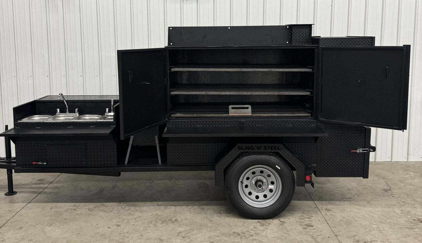 SNS 60 Cabinet black steel smoker with sink, deep fryer, and multiple cooking racks on a trailer