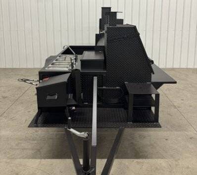 Black offset smoker BBQ catering trailer with multiple cooking compartments and prep areas on a diamond tread steel base