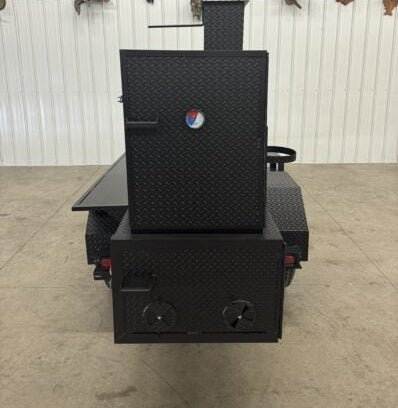 Black SNS Barrel 60 reverse flow smoker and charcoal grill with insulated firebox and adjustable smoke stacks on a trailer.