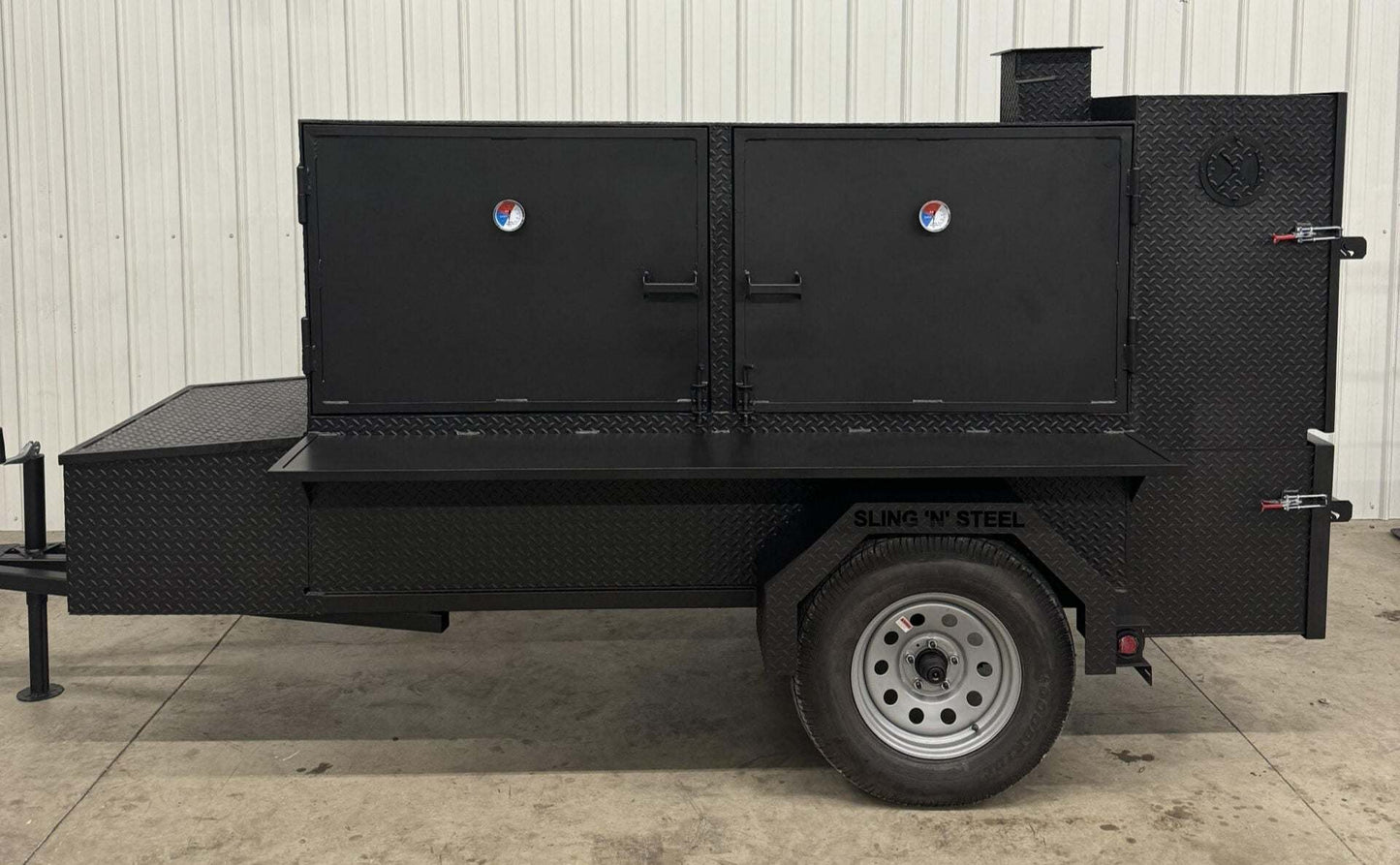 Black SNS Beast Cabinet Smoker with dual doors, diamond tread steel construction, mounted on trailer with single wheel, designed for large capacity barbecue cooking.