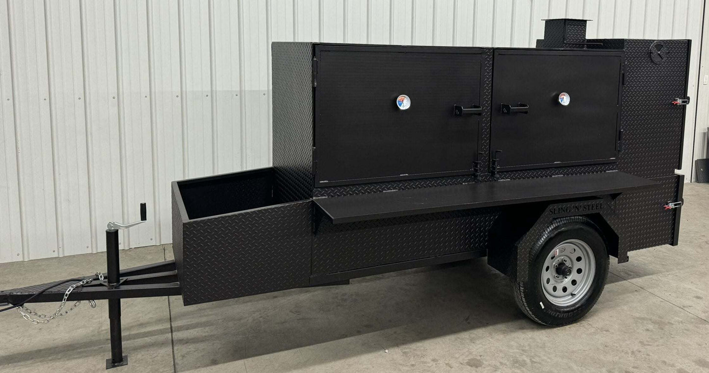 Large black SNS Beast cabinet smoker on trailer with dual cooking chambers, slide-out racks, firebox, warming box, and storage basket, designed for heavy-duty outdoor smoking and cooking.