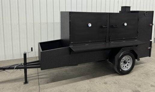 Large black SNS Beast Cabinet Smoker trailer with dual doors, storage basket, and wheels designed for heavy-duty smoking with multiple slide-out racks.