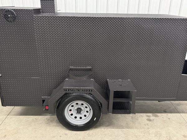 Close-up of SNS Beast Cabinet Smoker's black diamond tread steel exterior with tire and side firebox section