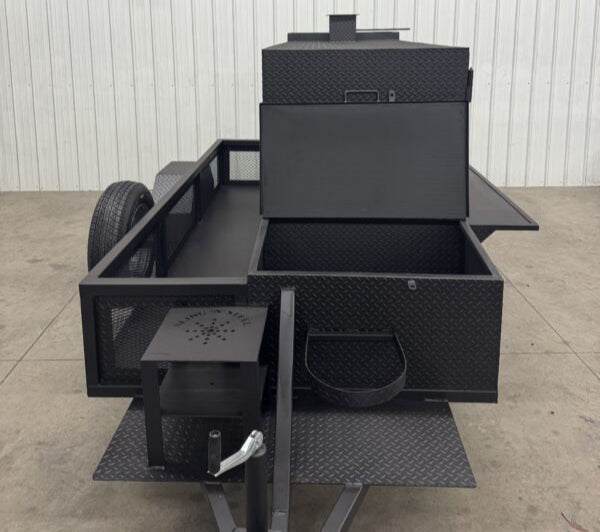 Black SNS Beast cabinet wood smoker with full-length storage and attached firebox on trailer platform
