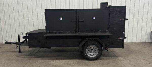 Large black SNS Beast Cabinet Smoker on trailer with full-length storage and multiple compartments for cooking and warming food