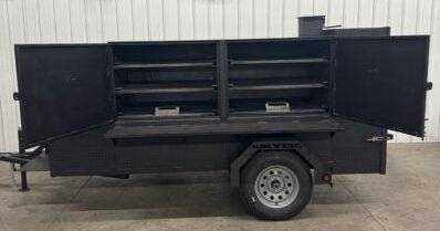 SNS Beast Cabinet Smoker with full-length storage, six slide-out racks, insulated firebox, warming box, and mounted fish fryer on trailer.