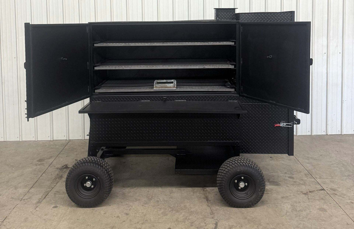 Black SNS Cabinet 60 Wagon Competition Smoker with open double doors, three slide-out cooking racks, and large wheels for mobility.