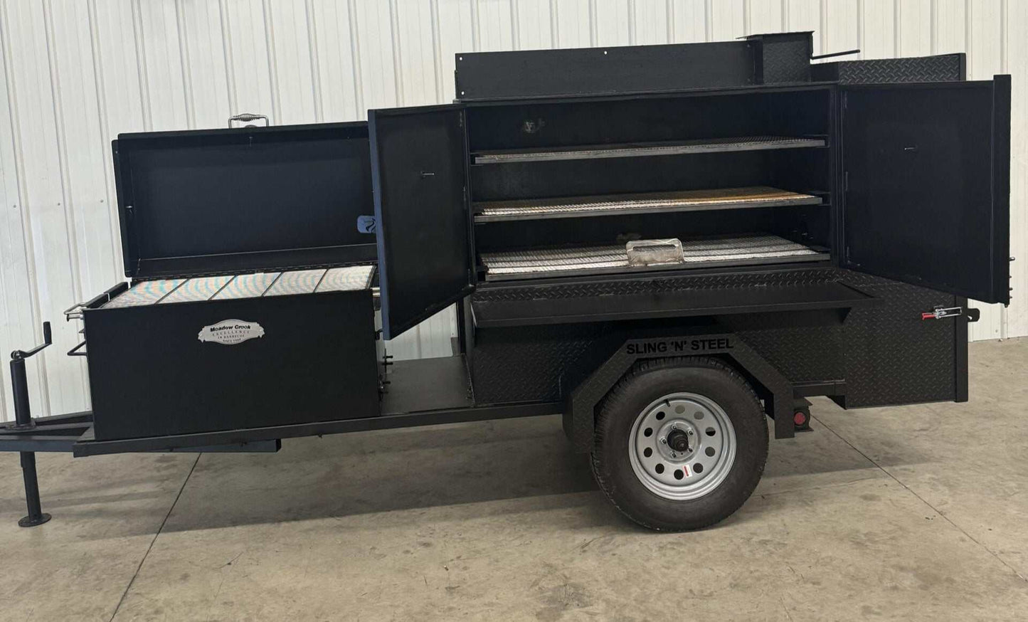 Wood fired smoker SNS Competition 60 Cabinet Smoker trailer with open doors showing multiple cooking racks and firebox on a single axle trailer