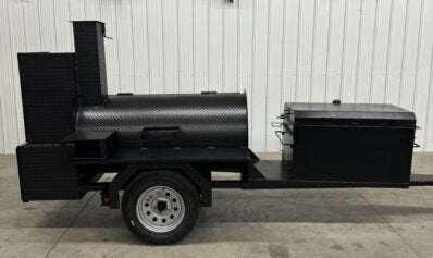 Custom Pits SNS Competition 60 charcoal smoker with 42-inch rotating stainless steel rack and insulated firebox on a single-axle trailer for commercial BBQ catering.