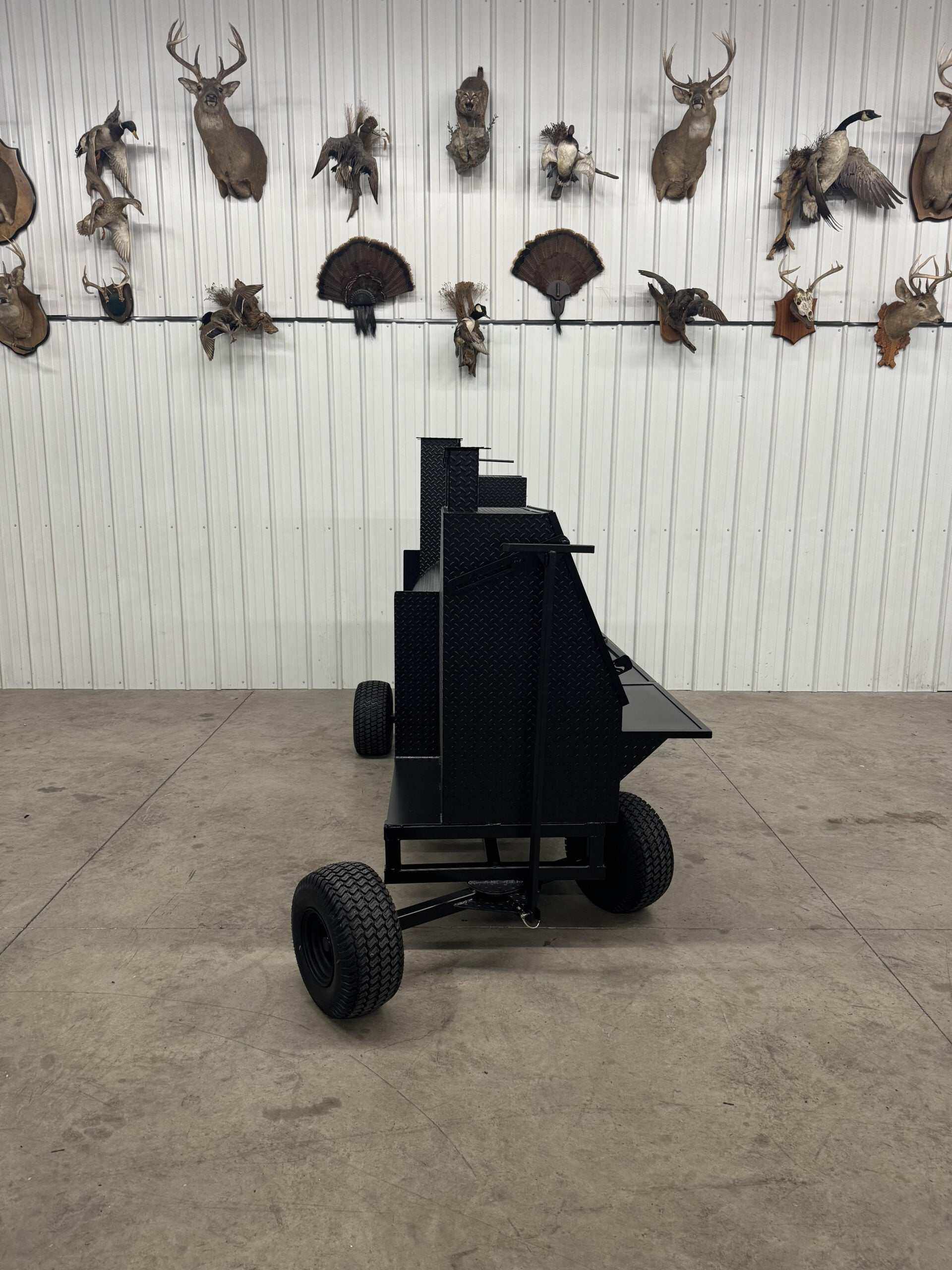 Backyard BBQ Smokers SNS Competition Wagon Smoker with large cooking racks and wagon chassis in indoor setting