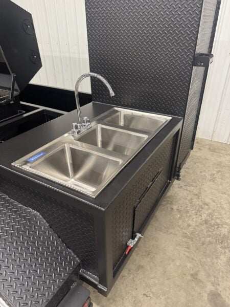 SNS Hospitality BBQ Trailer with triple-basin stainless steel sink and black diamond plate exterior for catering and outdoor events.