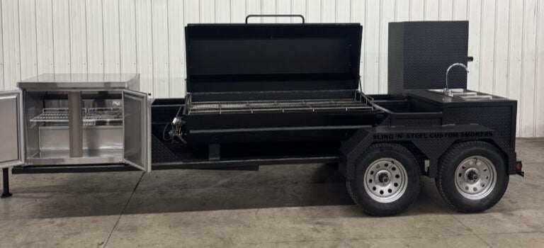 SNS Hospitality BBQ trailer with propane gas grill, refrigerator, storage compartments, and 3-bay sink system for large outdoor cooking events.