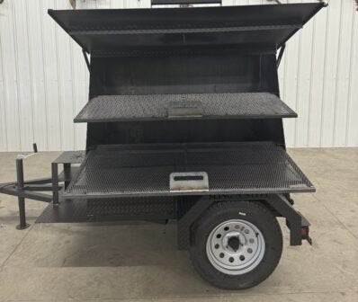 Black SNS Mega Grill dual-pit grilling trailer with pull-out charcoal trays and two cooking racks, designed for catering and outdoor grilling.