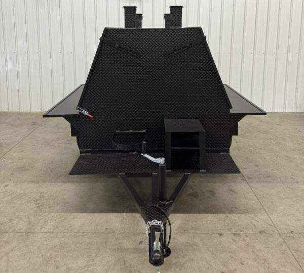 Front view of SNS Mega Grill black metal grilling trailer with dual chimney stacks and hitch tow assembly