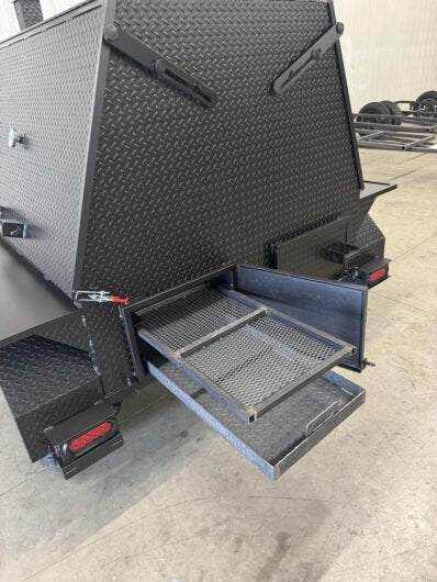 SNS Mega Grill commercial grilling trailer with dual pull-out charcoal trays and ash pans for BBQ catering.