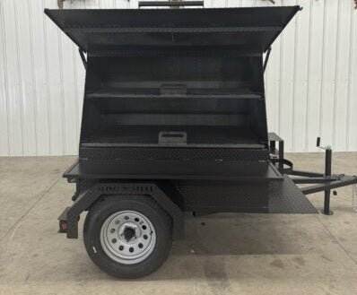 SNS Mega Grill black grilling trailer with dual cooking pits and pull-out charcoal trays for commercial BBQ catering and outdoor cooking