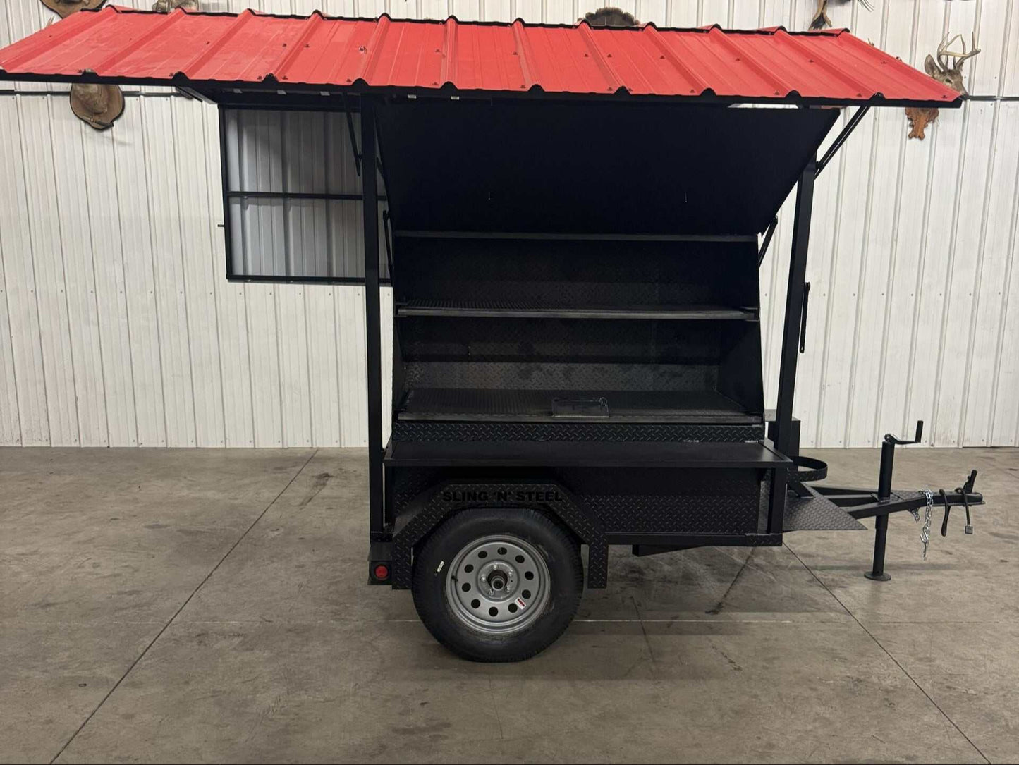 Outdoor SNS Mega Grill catering trailer with dual cooking pits, pull-out charcoal trays, roof, and fryer stand.