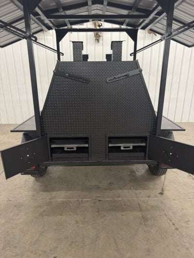Giant SNS Mega Grill with dual cooking pits, roof, pull out charcoal trays, and ash pans in a commercial trailer setup