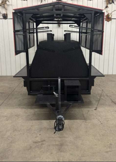 Large black SNS Mega Giant Grill commercial cooking trailer with dual grilling pits and attached roof package in indoor setting
