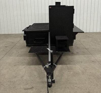 SNS Smoke House Smoke Cabinet Smoker with flat grill and trailer hitch in black textured steel.