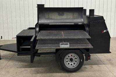 Custom BBQ trailer with dual cooking pits, charcoal trays, pull-out racks, storage compartment, and commercial-grade smoker tank on trailer wheels