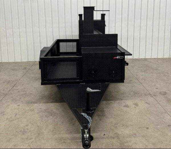 Front view of a black custom BBQ trailer with dual cooking pits and storage compartments designed for commercial catering.