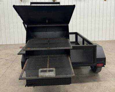 Custom BBQ trailer with dual cooking pits, slide-out charcoal trays, storage area, and fryer stand for commercial catering.