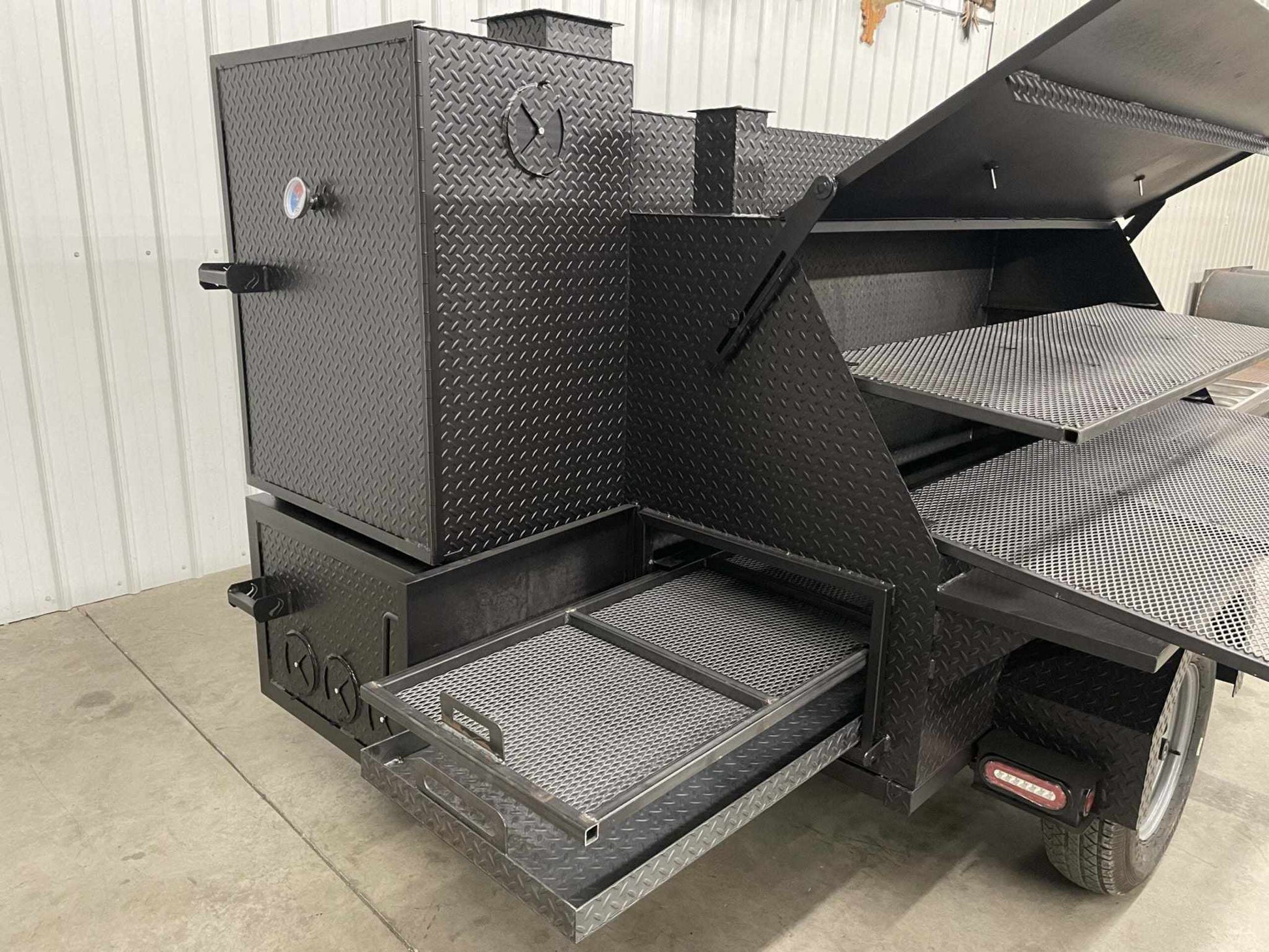 SNS Ultimate Smokehouse 60-inch charcoal grill with griddle, pullout racks, insulated firebox, sink, and fryer on wheels