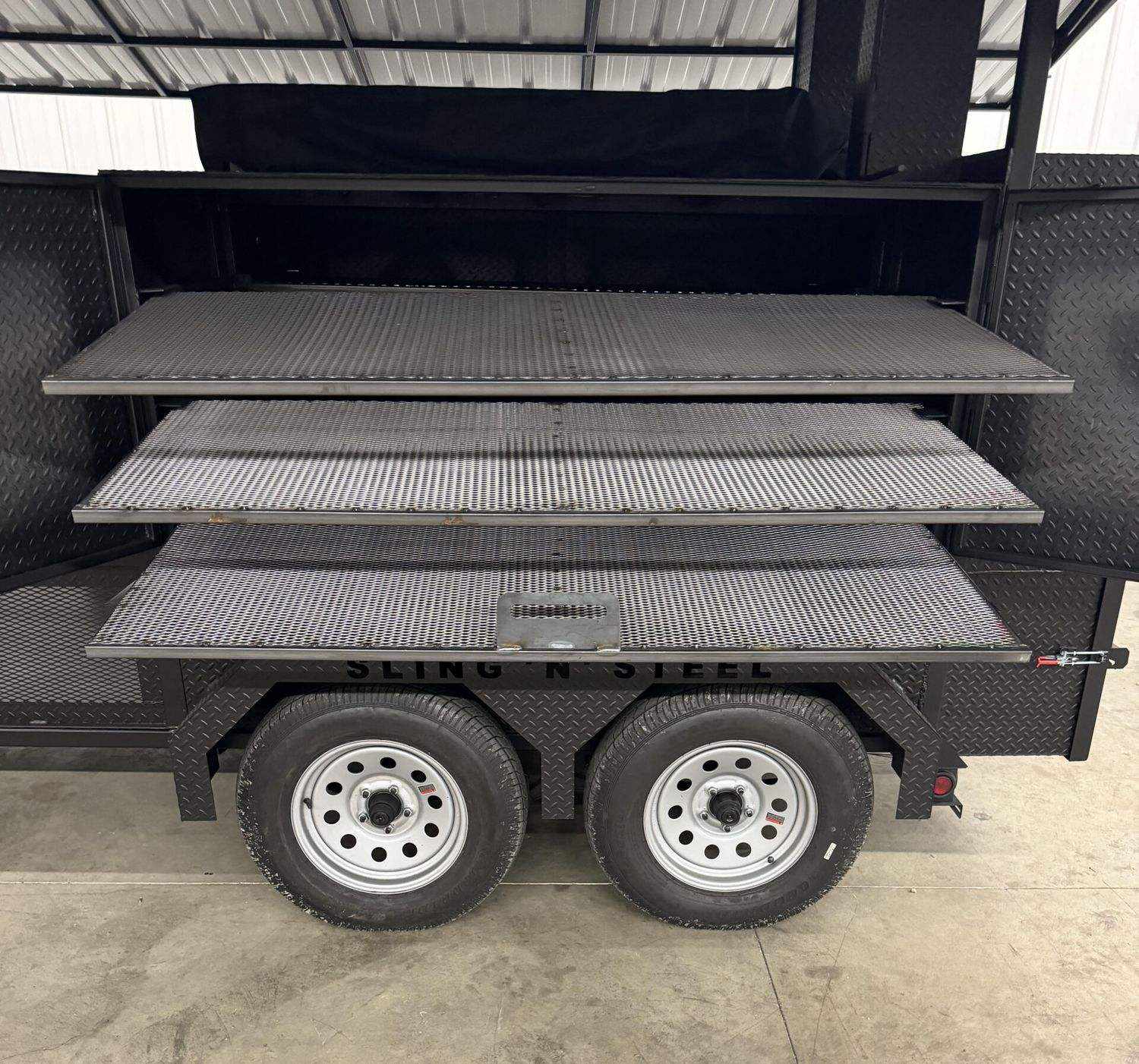 Commercial Smoker Avery with large cooking chamber, multiple racks, steel wheels, and insulated firebox on trailer