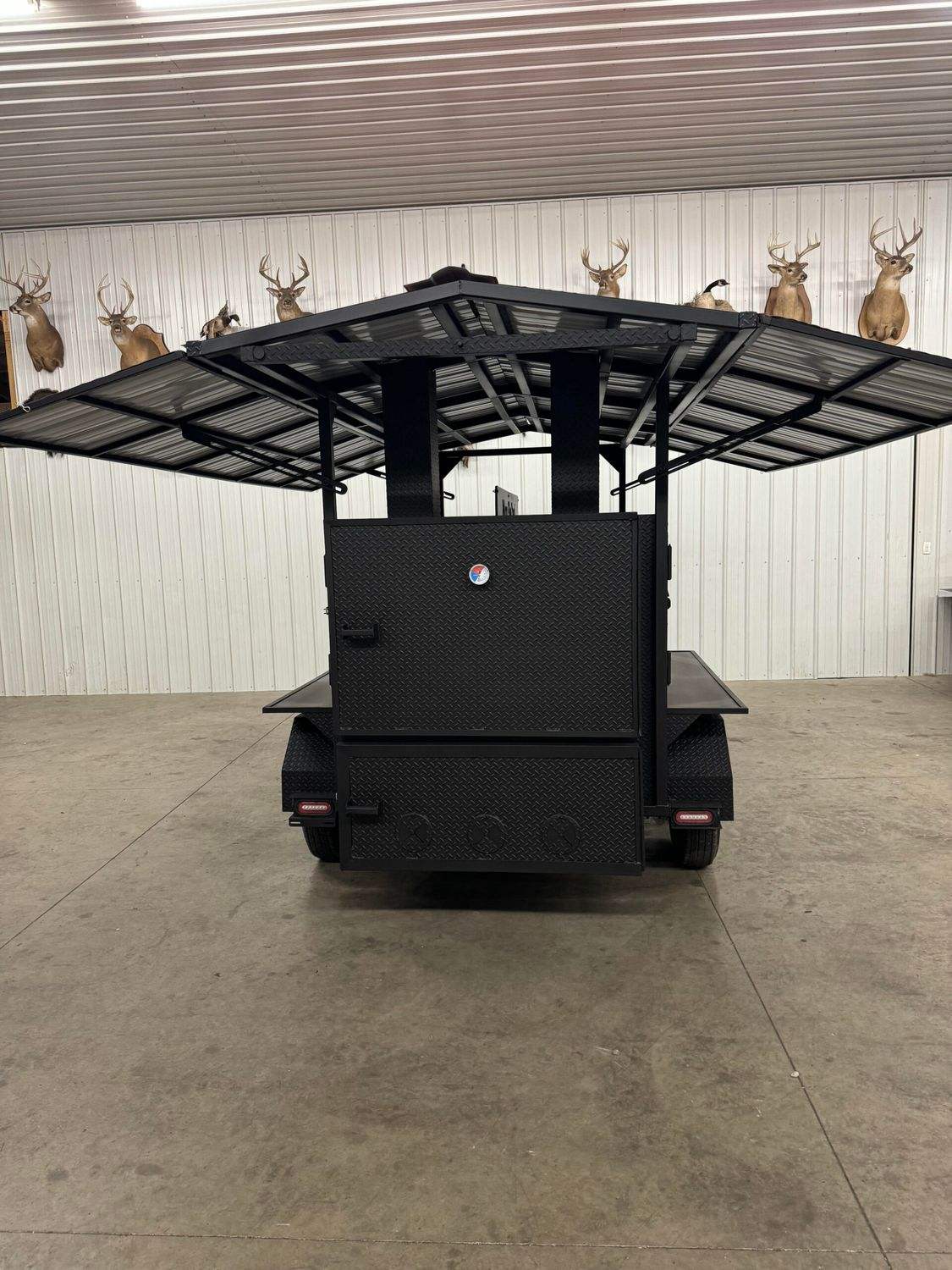 Commercial Avery cabinet smoker with large cooking chamber and fold-out roof panels in indoor space