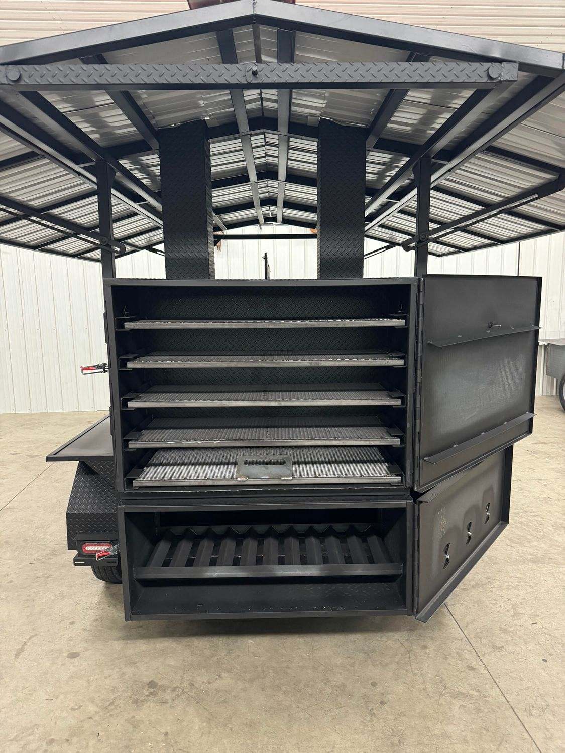 Large commercial Avery cabinet smoker with multiple cooking racks and storage compartments inside a covered industrial setting