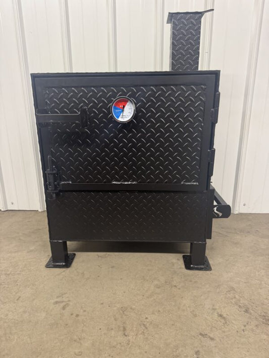 Black metal barbecue grill with a logo on a concrete floor against a white wall.