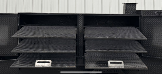 Large black cabinet smoker on stands with multiple slide-out cooking racks and warming box trays designed for high-capacity smoking of meats