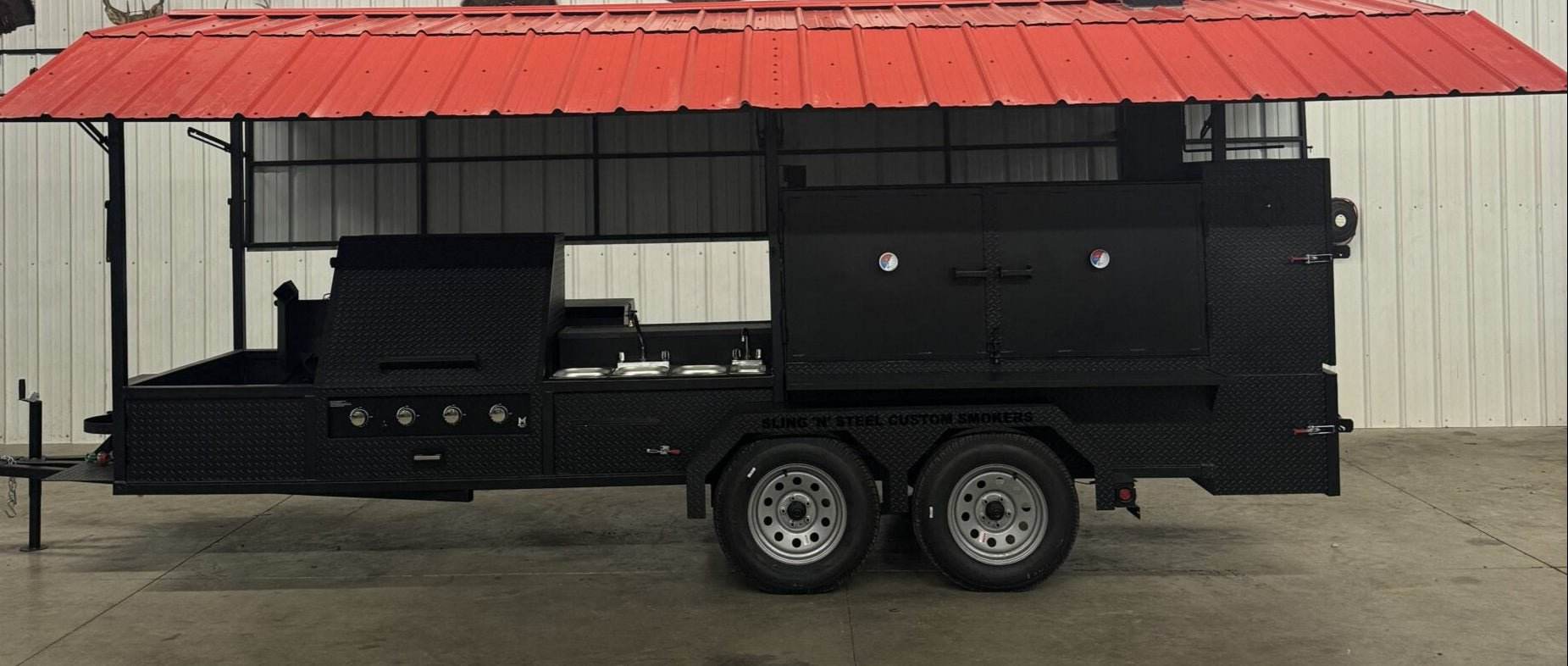 Ultimate Smokehouse 72-inch black smoker on trailer with red roof, sinks, griddle, and charcoal grill for large capacity BBQ cooking