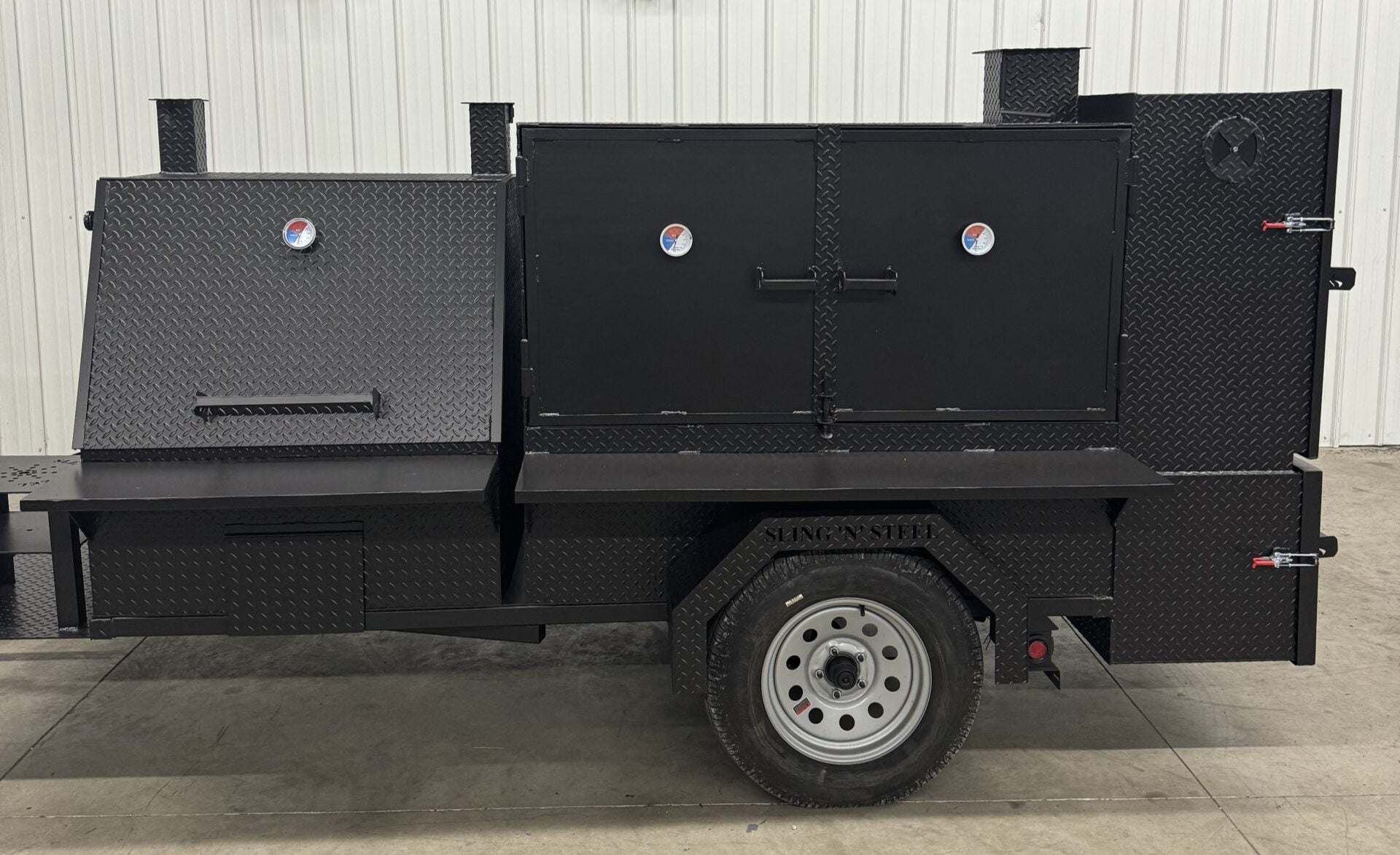 Black SNS 4060 smoker grill and cabinet main chamber with dual fryer stands and wheels for catering use